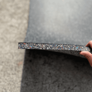 Commercial Standard Exercise mat- Flooring Mat (1000MM*1000MM*20MM) on floor with side layer visible with multi-colour particles- held horizontally in place with a hand (partly visible)