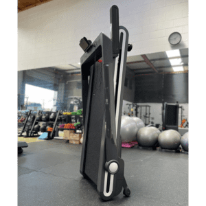 Rent Gym Equipment- (300*300)- Profile view of the Assemble free Foldable treadmill in folded position placed vertically in gym setting
