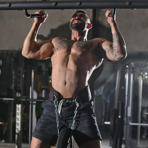 Weight Lifting Gear- View of a man equipped with weight lifting belt with chain and black weight plate attached performing a pullup