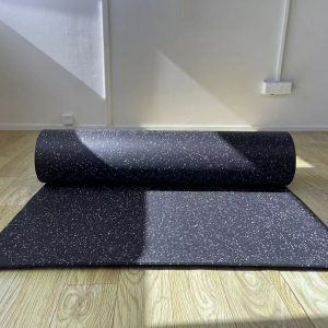 Gym Accessories- (300*300)- Front view of a partially unrolled Black Flooring Mat (7000MM*1000MM*5MM) with multi-colour particles visible, placed on wooden floor