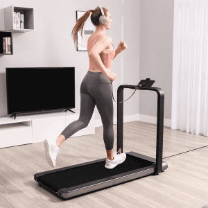 Cardio Equipment- Woman running on the WalkingPad x21 Double-Fold Treadmill in an indoor setting wearing white over-ear headphones (High Resolution Image)