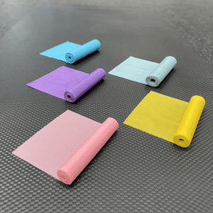 Weight Lifting Accessories- 5 partially unwound Flat Resistance Bands of colours Blue, Grey, Purple, Yellow and Pink placed on a gym floor alternatively