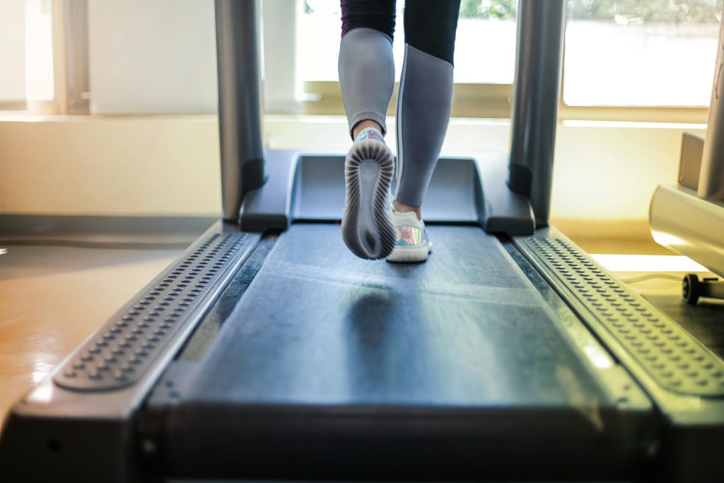 Close-up of a person's legs and feet in athletic wear and running shoes, actively exercising on a treadmill, highlighting fitness and healthy lifestyle.